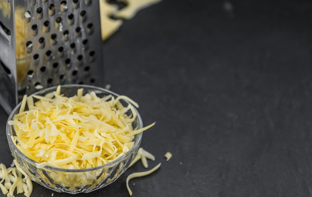 Nahaufnahme von hausgemachtem geriebenem Käse auf einer Schieferplatte