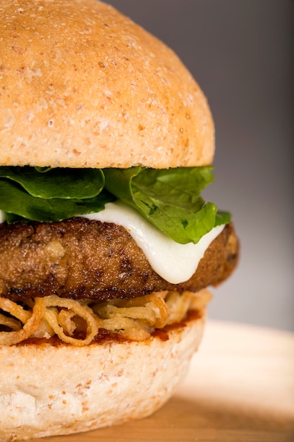 Nahaufnahme von hausgemachten leckeren Burgern mit Rindfleisch, Käse, Rucola auf Holztisch. Cranberry scharfe Sauce.