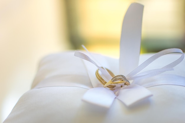 Nahaufnahme von Hochzeitsringen auf einem Kissen zu Hause