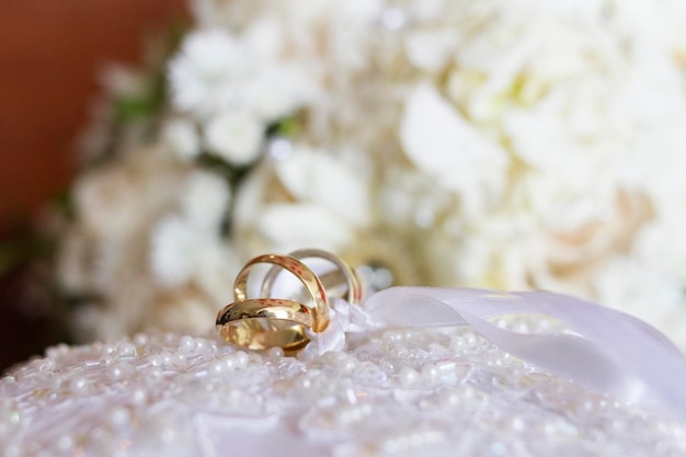 Nahaufnahme von Hochzeitsringen mit einem Blumenstrauß im Hintergrund