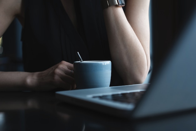 Nahaufnahme von jungen, schönen, nicht erkennbaren Frauenhänden, die eine heiße Tasse Kaffee oder Tee halten.