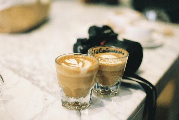 Foto nahaufnahme von kaffeegläsern und kamera auf dem tisch