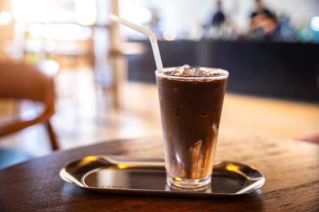 Nahaufnahme von Kakaoeis im Becher auf Glas im Holzschreibtisch im Café im Café im Garten während des Geschäftsarbeitskonzepts