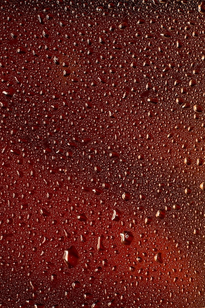 Nahaufnahme von kalten Tropfen auf dem Glas Bierhintergrund. Textur des kühlenden Alkoholgetränks mit Makroblasen an der Glaswand. Zischend oder schwimmend bis zur Oberfläche. Dunkelbraun gefärbt.