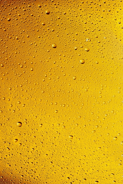 Nahaufnahme von kalten Tropfen auf dem Glas Bierhintergrund. Textur des kühlenden Alkoholgetränks mit Makroblasen an der Glaswand. Zischend oder schwimmend bis zur Oberfläche. Goldfarben.