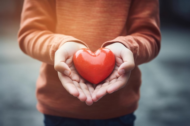 Nahaufnahme von Kinderhänden, die ein rotes Herz halten Ein Junge mit einem roten Herz Symbol des Muttertages der Liebe