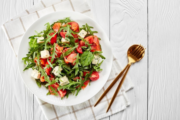 Nahaufnahme von köstlichen gesunden Lachs-Rucola-Blauschimmelkäse-Tomaten-Salat auf einem weißen Teller