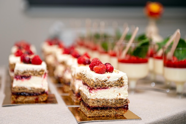 Nahaufnahme von Kuchen mit frischen Früchten und Beeren, die in einer Reihe auf einem Partytisch angeordnet sind