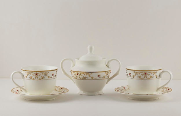 Nahaufnahme von kunstvoll gefertigten Keramik-Teetassen und einem Topf mit goldenen Verzierungen
