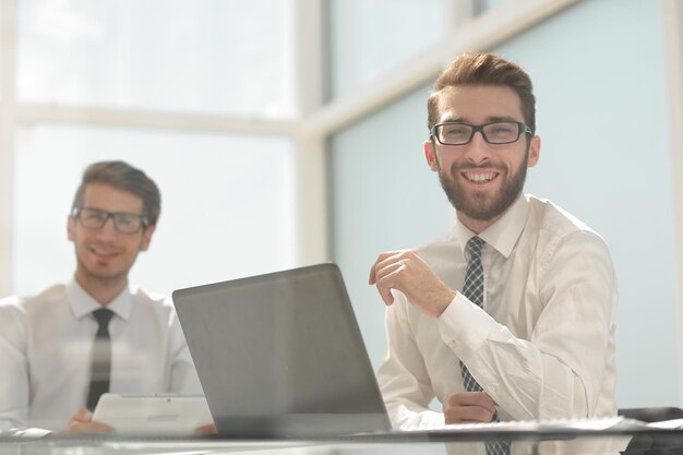 Nahaufnahme von lächelnden Geschäftskollegen, die am Deskphoto mit Platz für Text sitzen