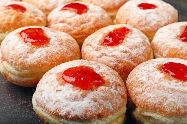 Nahaufnahme von leckeren Donuts mit Marmelade auf dunklem Hintergrund. Chanukka-Feierkonzept