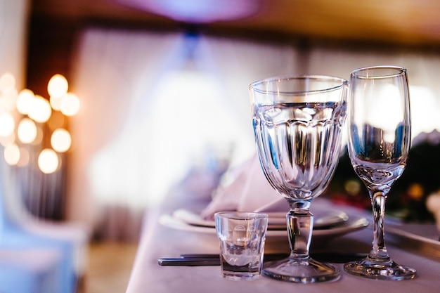 Nahaufnahme von leeren Gläsern im Restaurant und Besteck Besteck oder Besteck auf Tellern Gläser für Champagner- und Weingläser Reflektion Bokeh und helles Licht