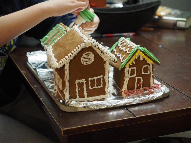 Foto nahaufnahme von mädchen, die gingerbread-häusern mit der hand glasur hinzufügen