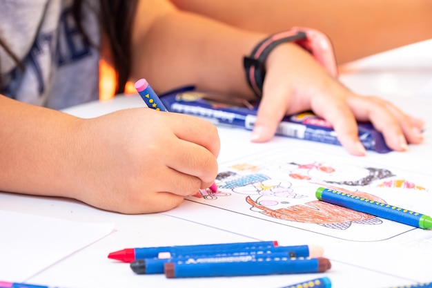 Nahaufnahme von Mädchen, die mit den Händen Kerzen auf weißem Farbpapier färben, Kinderkunstwerke für Meditation, frühkindliche Bildung, Kopierraum