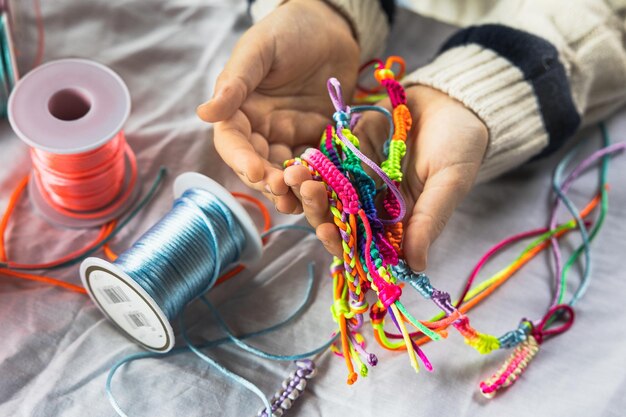 Nahaufnahme von Mädchenhänden mit ihrem handgefertigten Armband in leuchtenden Farben