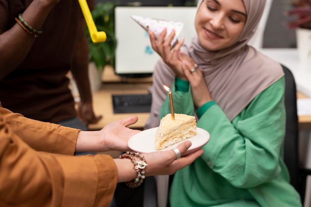 Nahaufnahme von Menschen, die Kollegen mit Kuchen feiern