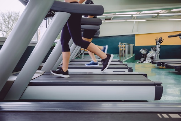 Nahaufnahme von Menschenbeinen, die in einer Trainingseinheit im Fitnesscenter über Laufband laufen?