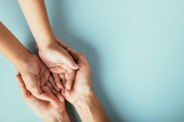 Foto nahaufnahme von oben von familienhänden auf einem isolierten hintergrund eltern und kind halten einen leeren raum, der unterstützung und liebe am tag der familie und der eltern symbolisiert