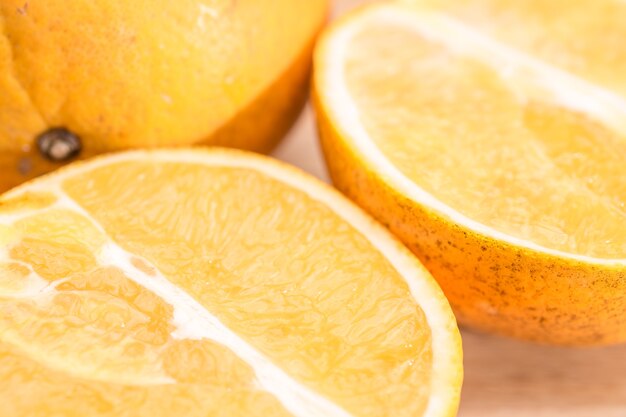 Nahaufnahme von Orangenscheiben auf einem Holzschneidebrett in der Küche in der Sonne mit einem scharfen Kontrast von Licht und Schatten in hellen, lebendigen und warmen Farben.