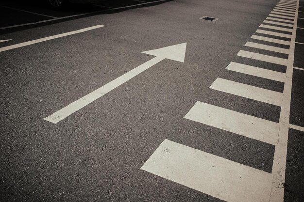 Nahaufnahme von Pfeil- und Fußgängerübergangsmarkierungen auf der Straße