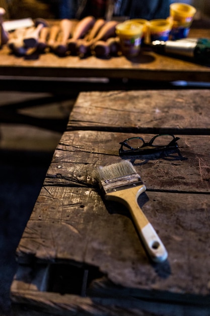 Nahaufnahme von Pinsel und Brille auf einem Holztisch