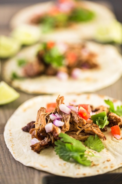 Nahaufnahme von Pulled Pork Carnitas mit Pico de Gallo auf einer Mehltortilla.