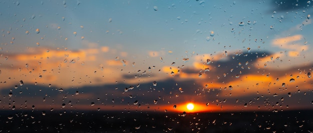 Nahaufnahme von Regentropfen auf Fenster auf Hintergrund der schönen bunten Sonnenuntergang Natürlicher abstrakter Hintergrund Panorama-Banner-Ansicht