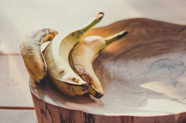 Nahaufnahme von reifen Bananen, die auf einem Holzstumpf unter dem Konzeptfoto des Sonnenlichts liegen