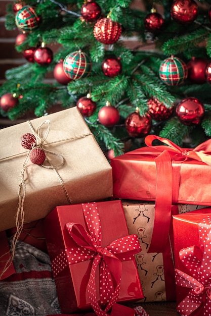 Nahaufnahme von roten Geschenkboxen in der Nähe eines Weihnachtsbaumes mit roten Weihnachtskugeln.