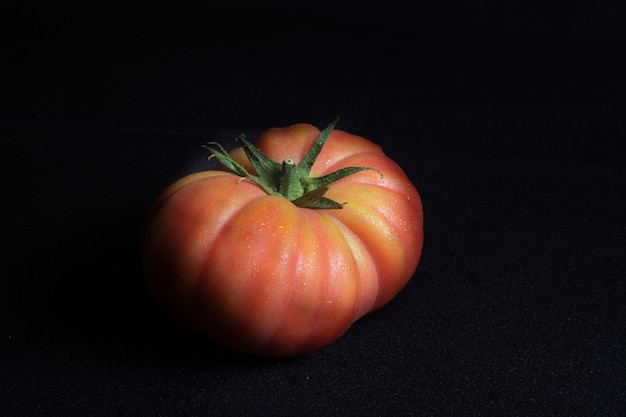 Nahaufnahme von saftigen, roten Tomaten auf einer schwarzen Oberfläche