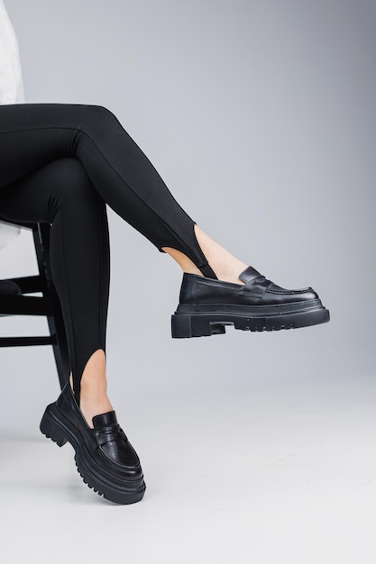 Nahaufnahme von schlanken weiblichen Beinen in schwarzen Leggings und schwarzen Lederschuhen Neue Frühjahrs- und Sommerkollektion von Lederschuhen für Damen