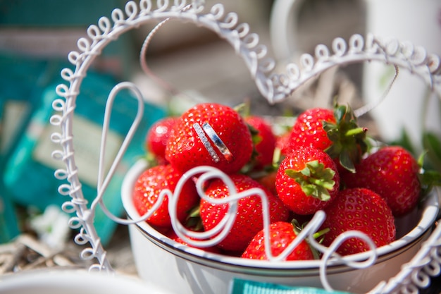 Nahaufnahme von schönen Eheringen stehen von den Erdbeeren in einem Vase mit einem Erdbeerrutschen, selektiver Fokus hervor