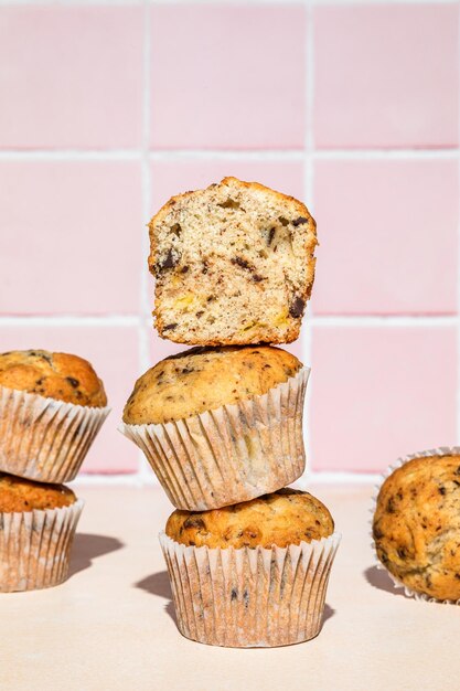 Nahaufnahme von Schokoladen- und Bananenmuffins im Stapel geschossen auf buntem Hintergrund, hartes Licht, vertikal