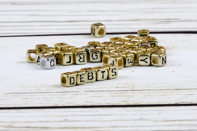 Foto nahaufnahme von schuldentext mit goldenen spielzeugblöcken auf dem tisch