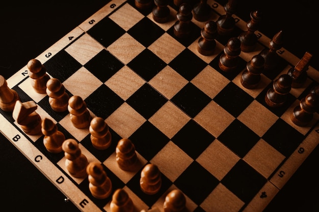 Nahaufnahme von schwarzen Schachfiguren an Bord Zwei Reihen von Holzfiguren auf Schachbrett auf schwarzem Hintergrund Konzept des intelligenten logischen und strategischen Spiels