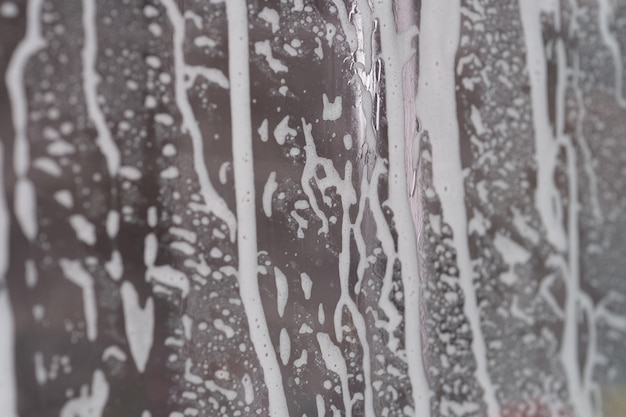 Nahaufnahme von Seifenschaum auf transparentem Glas im Badezimmerhintergrund