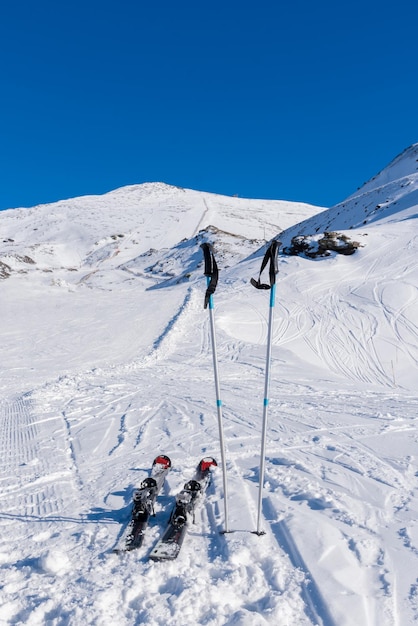 Nahaufnahme von Skiern und Stöcken, die inmitten eines schneebedeckten Berges im Schnee stecken