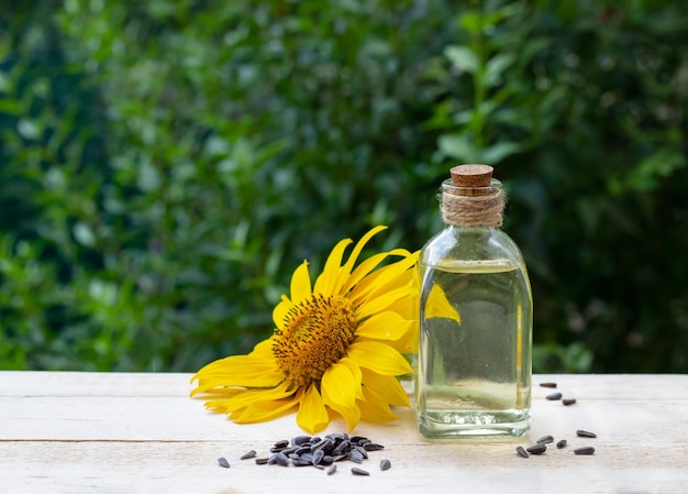 Nahaufnahme von Sonnenblumenöl in einem Flaschenglas mit Samen und Sonnenblumen