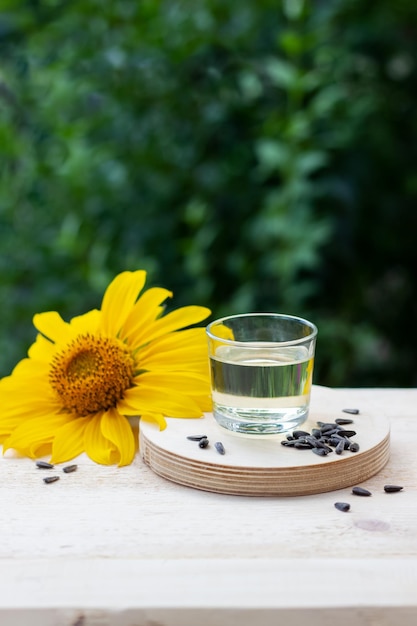 Nahaufnahme von Sonnenblumenöl in einem Glas mit Samen und Sonnenblumen