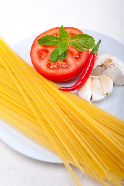 Nahaufnahme von Spaghetti und Tomaten mit Chili und Knoblauch auf dem Teller auf dem Tisch