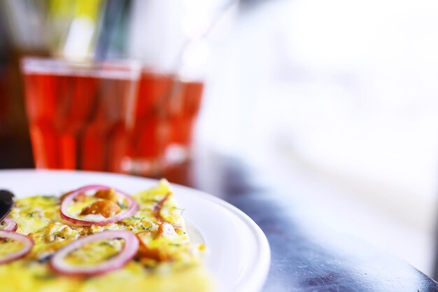 Nahaufnahme von Speckpizza, Orangensaft in einem Glas auf dem Tisch in einem Café in einem Restaurant