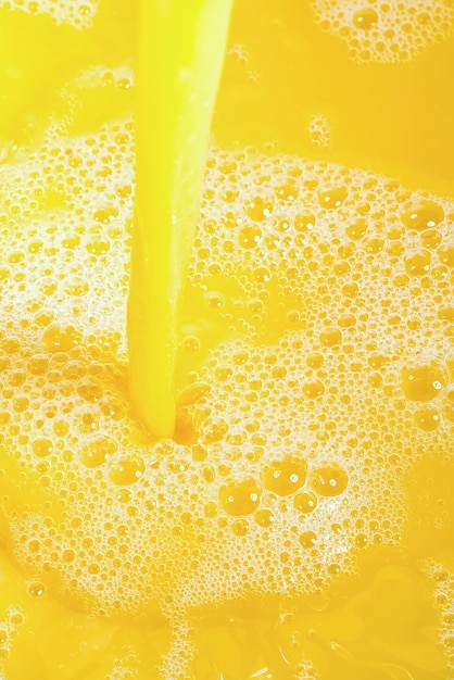 Nahaufnahme von spritzendem Orangensaft von oben Spritzer von frischem süßem Orangen-Mango-Fruchtsaft