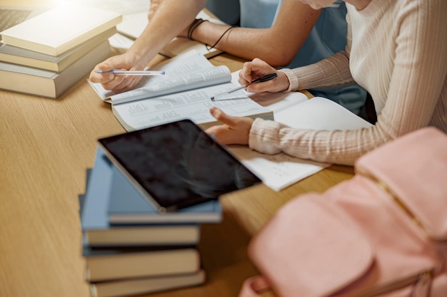 Nahaufnahme von Studenten, die gemeinsam an einem Universitätsprojekt arbeiten und in der Bibliothek sitzen