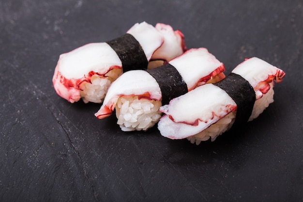 Nahaufnahme von Tako Nigiri Sushi mit gekochtem Tintenfisch auf schwarzem Schieferhintergrund