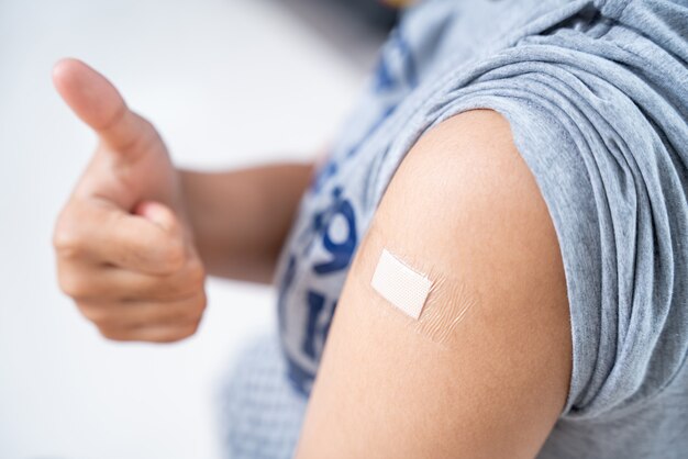 Nahaufnahme von Teenager-Mädchen in der Schulter mit Pflaster am Arm nach der Impfung im Krankenhaus