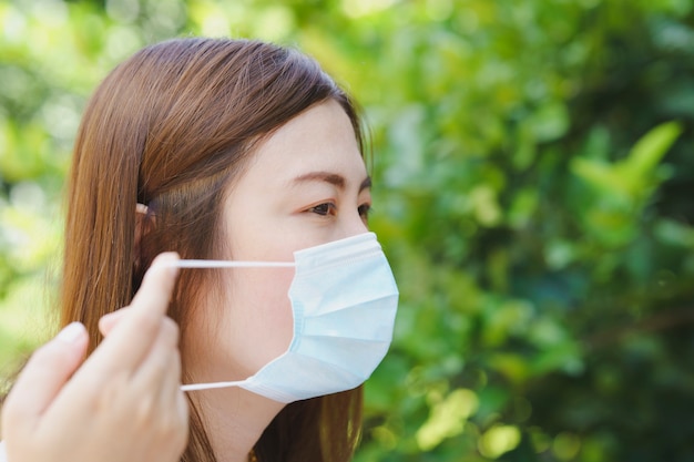 Nahaufnahme von thailändischen Frauen, die Maskenseitenansicht mit natürlichem Unschärfehintergrund tragen