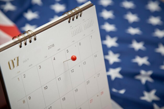 Nahaufnahme von Thumbtack über Kalender auf amerikanischer Flagge