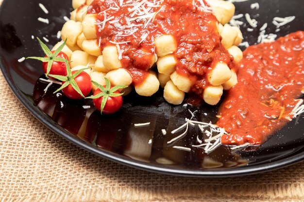 Nahaufnahme von traditionellen italienischen Kartoffelgnocchi in Tomatensauce mit Käse und Kirschtomaten