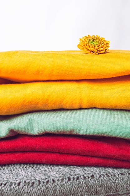 Nahaufnahme von trendigen Farben für kaltes Wetter, Herbst- und Winterpullover. Schichten von Rot, Grün, Gelb werden übereinander gestapelt. Ein Stapel farbiger warmer Kleidung.