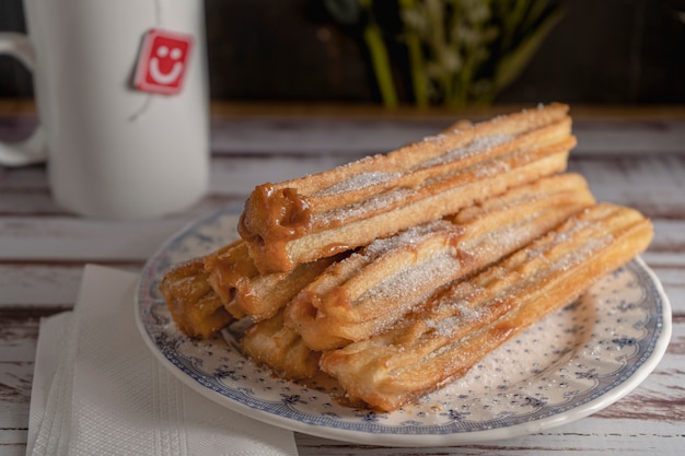 Nahaufnahme von typischen hispanischen Churros gefüllt mit Dulce de Leche in einem Vintage-Teller auf alten Brettern.